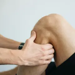 Fizjoterapeuta bada kolano pacjenta, oceniając uraz. Długość leczenia naderwanych więzadeł w kolanie zależy od stopnia uszkodzenia.