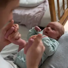 Ojciec delikatnie masuje stópki niemowlęcia, ćwicząc ruchy zgodne z metodą Vojty.