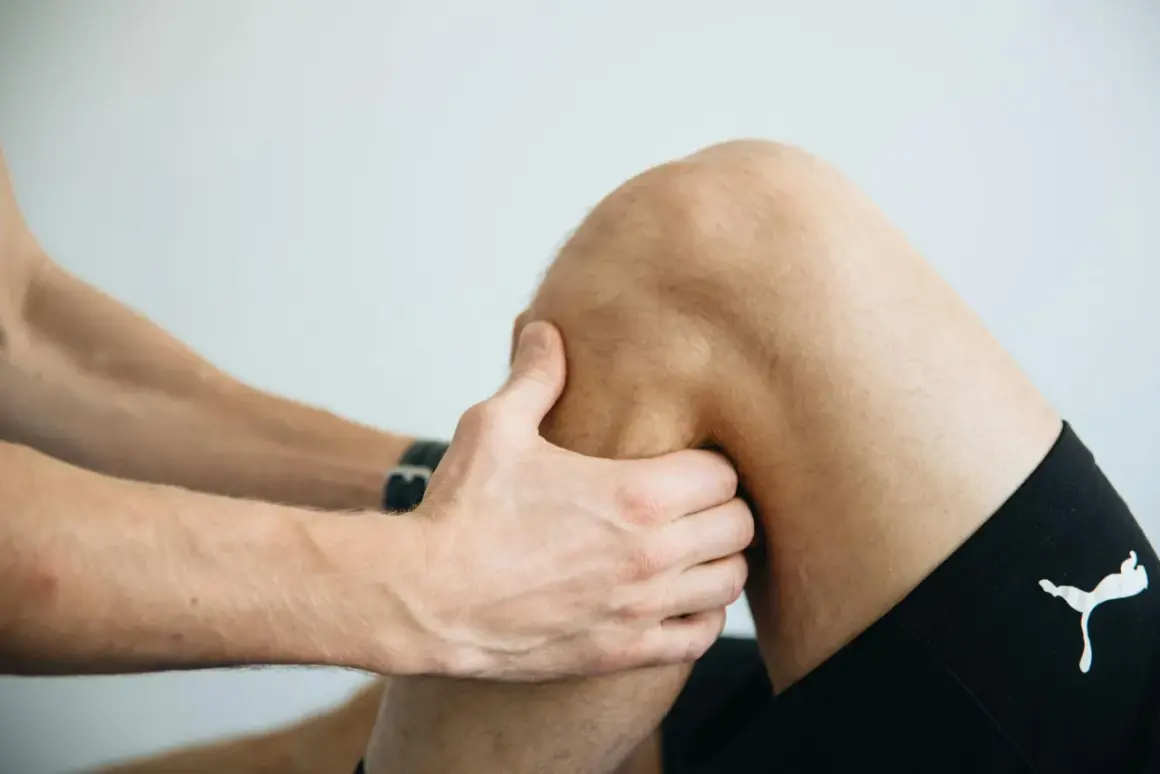 Fizjoterapeuta bada kolano pacjenta, oceniając uraz. Długość leczenia naderwanych więzadeł w kolanie zależy od stopnia uszkodzenia.