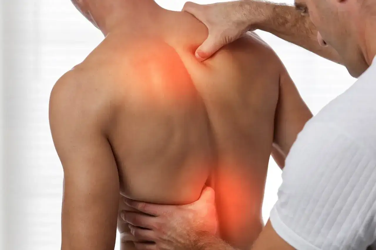 Chiropraktyka co to? Terapeuta uciska bolące plecy pacjenta, wskazując na problem.
