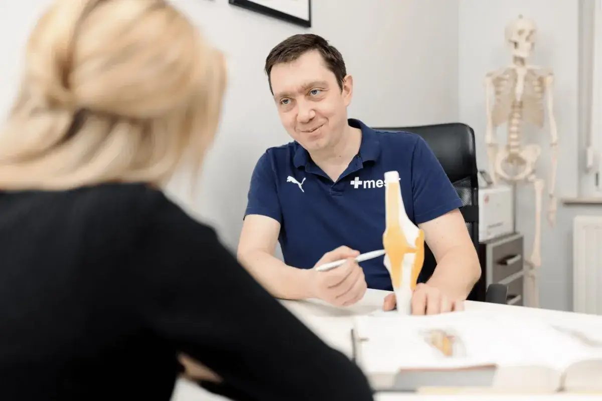 Lekarz omawia z pacjentką model stawu kolanowego, wyjaśniając zasady krioterapii miejscowej.