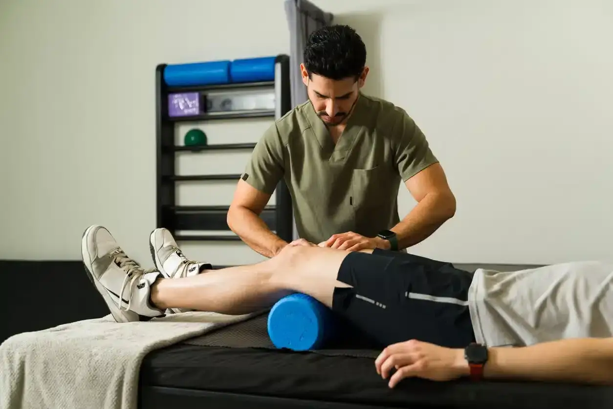 Fizjoterapeuta pracuje z pacjentem, który ma naderwane więzadła w kolanie. Leczenie może trwać od kilku tygodni do kilku miesięcy.